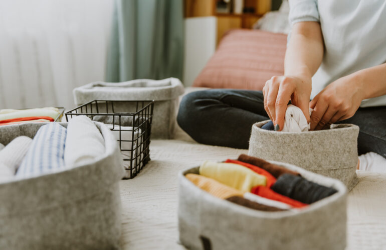 A person folding clothes in a basket for decluttering your house
