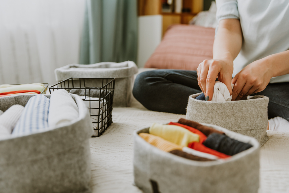 A person folding clothes in a basket for decluttering your house