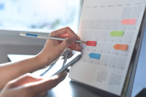 Image of person holding a pencil and a calendar planning for moving house 